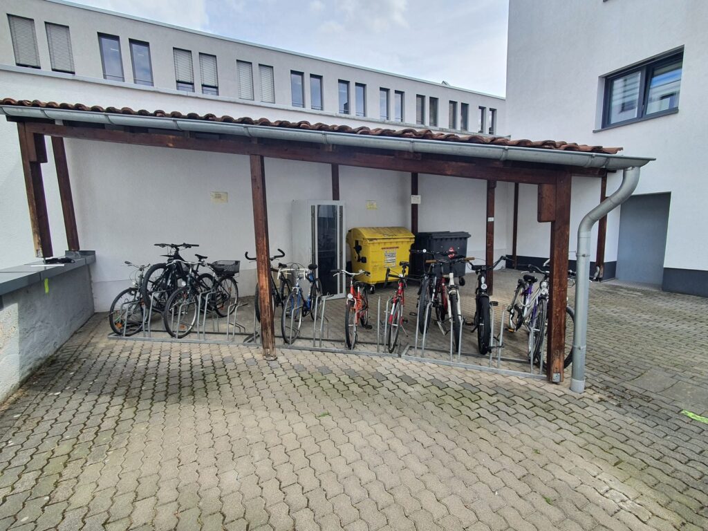 Überdachter Fahrradstellplatz mit Holzkonstruktion im Innenhof