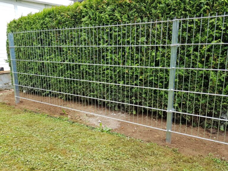 Frisch montierter verzinkter Doppelstabzaun vor einer Hecke