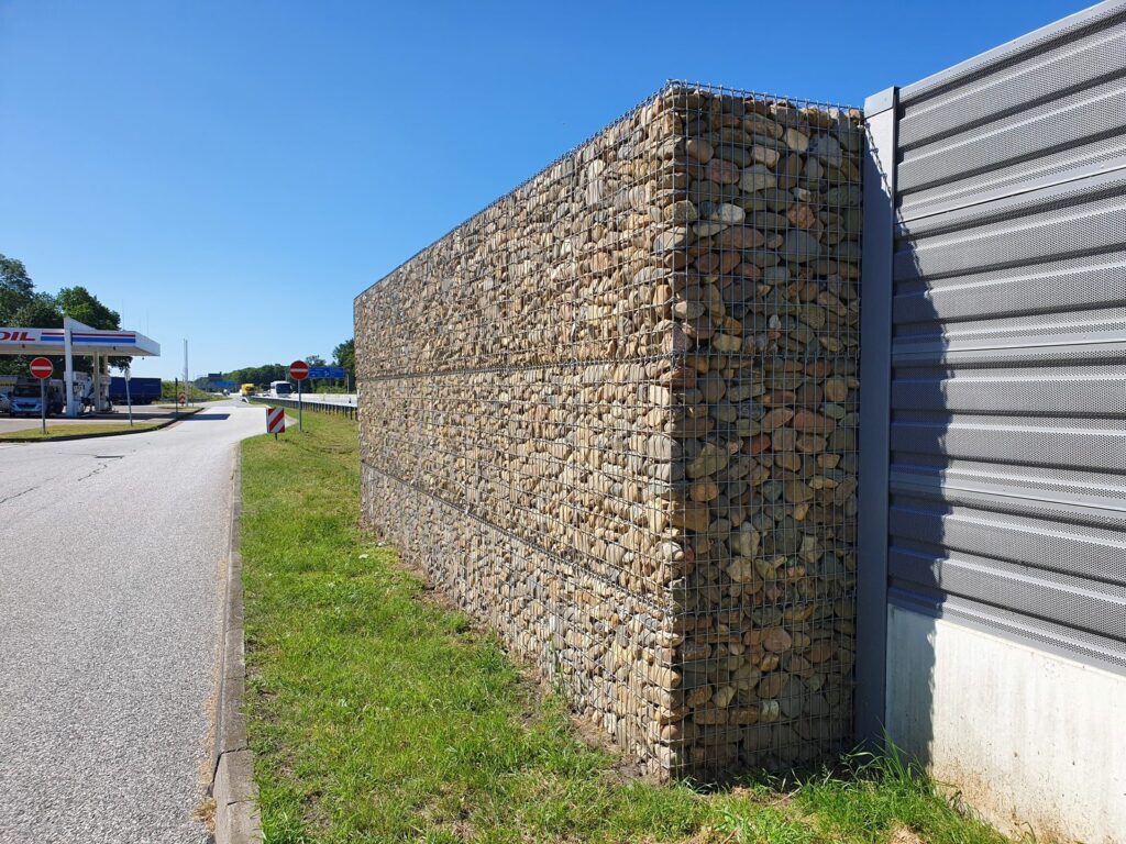 Gabionenwand entlang einer Straße, kombiniert mit Sichtschutzwand
