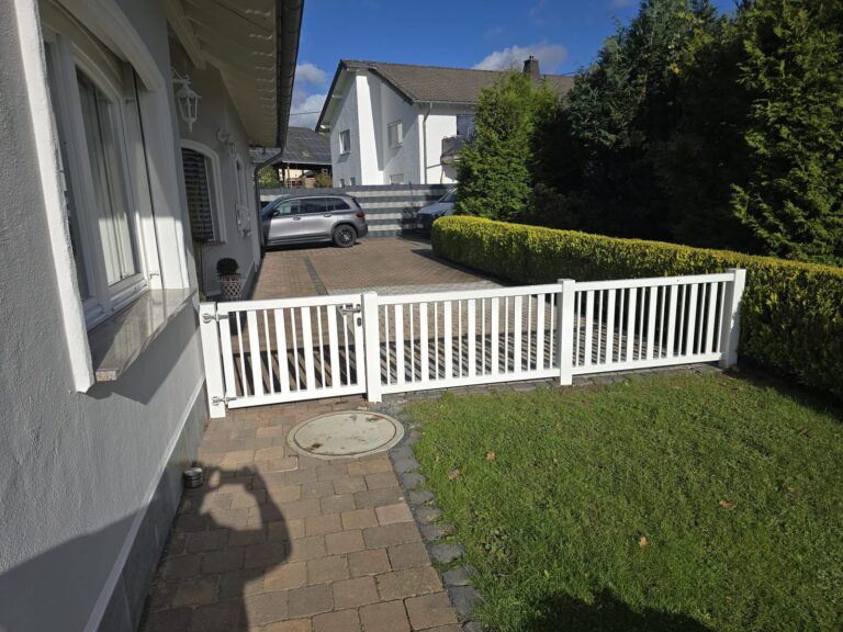 Weißer Zaun entlang der Einfahrt eines Wohnhauses