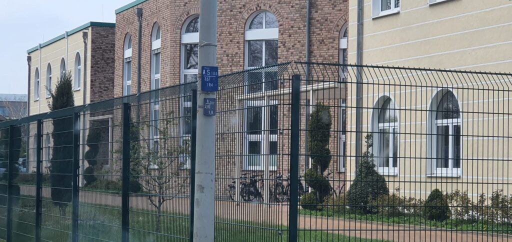 Doppelstabzaun mit abgeschrägter Oberkante vor einem öffentlichen Gebäude