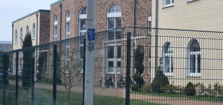 Doppelstabzaun mit abgeschrägter Oberkante vor einem öffentlichen Gebäude