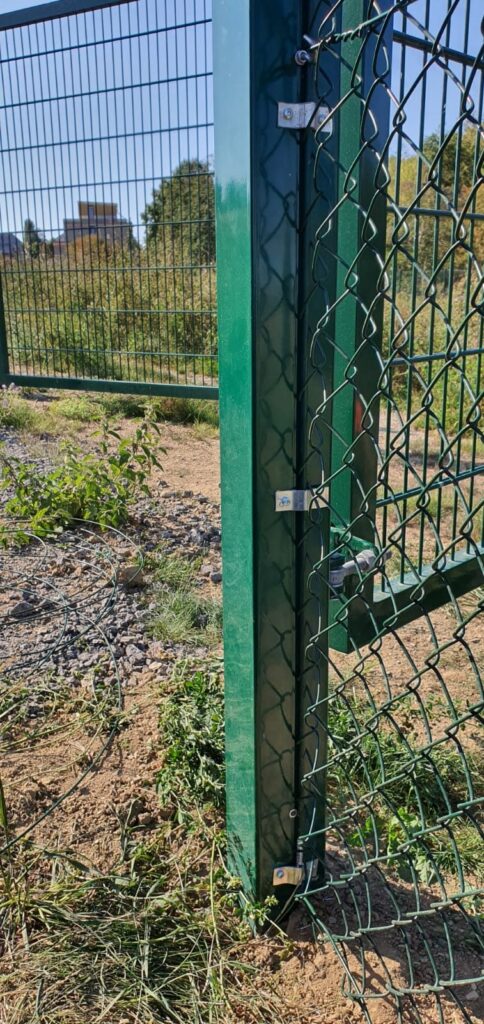 Grüner Maschendrahtzaun am Rundpfosten mit Spanndraht