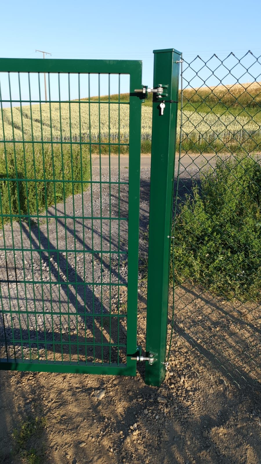 Grünes Tor in einem Maschendrahtzaun