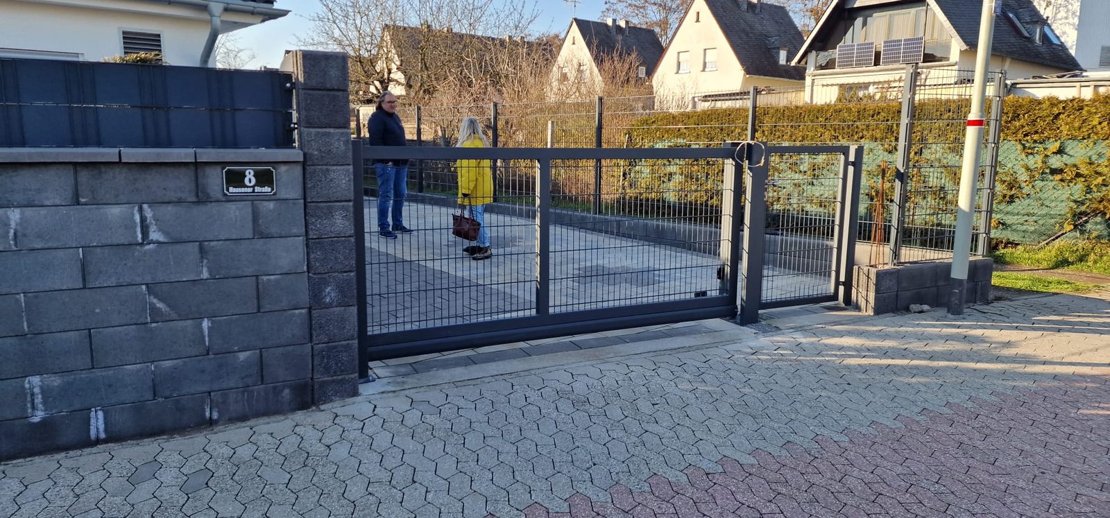 Monteur arbeitet an einem Schiebetor auf einer Betonsteinmauer