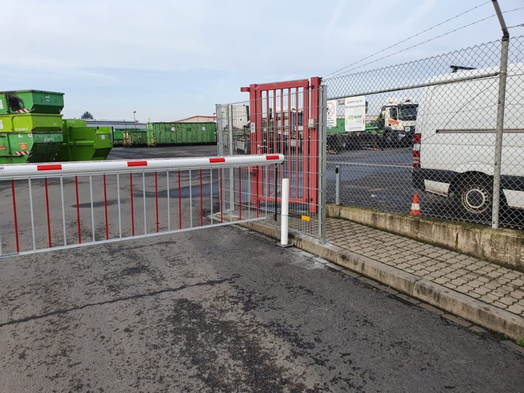 Schrankenanlage mit rotem Schiebetor an der Zufahrt eines Betriebsgeländes